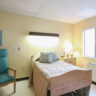 A clean and minimalist hospital room with a single bed and basic furnishings.