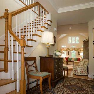 A cozy and traditionally decorated home with a wooden staircase leading into a warmly lit living room.