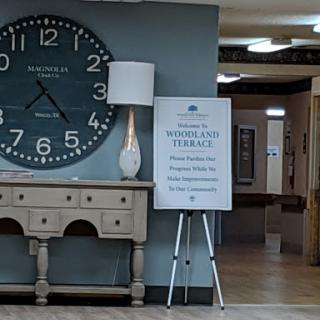 A modern lobby featuring a large wall clock, stylish furniture, and informative signage.