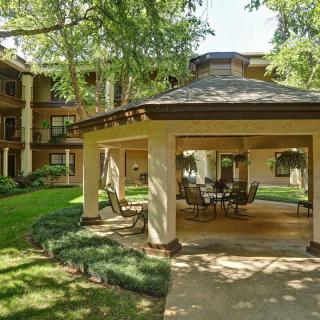 Outdoor gazebo area in a residential apartment complex surrounded by lush greenery.