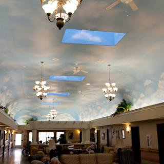 A beautifully designed lobby with a ceiling painted to resemble the sky, featuring chandeliers and comfortable seating.