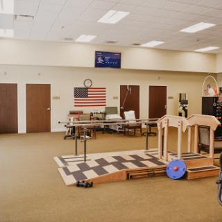 A spacious rehabilitation room featuring exercise equipment and an American flag on the wall.