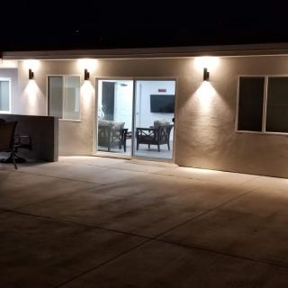 A well-lit patio area at night featuring a house exterior with glass doors and windows.