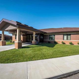 A modern brick clinic building with a welcoming entrance and well-maintained lawn.