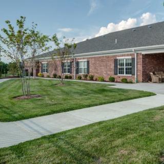 A brick building with a well-maintained lawn and sidewalk on a sunny day.