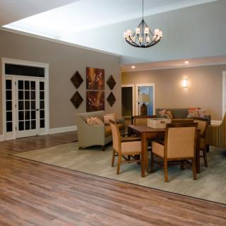 A modern living and dining area with wooden flooring, stylish furniture, and a decorative chandelier.