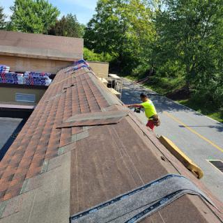 A worker installing roofing materials on a sunny day, showcasing the construction process.