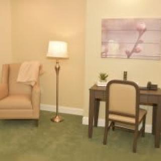 A cozy living space with a comfortable chair, floor lamp, and a sleek desk with artwork on the wall.