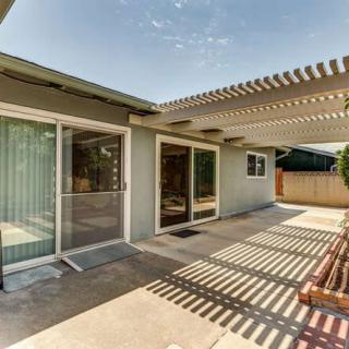 A residential outdoor patio area featuring a pergola and sliding glass doors.