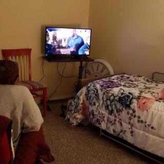 A cozy bedroom setup with a TV, bed, and chair.