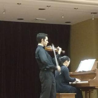 A violinist performing alongside a pianist during a musical duet.