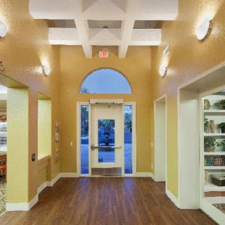An interior view of a well-lit hallway with an entrance door and wooden flooring.