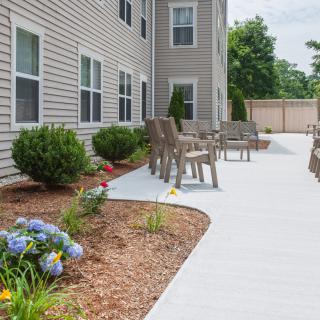 A well-maintained patio area with chairs and landscaped garden outside a building.