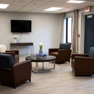 A modern waiting room with comfortable seating and a mounted TV.