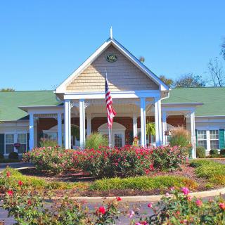 A charming residential building with a green roof, surrounded by a well-maintained garden and an American flag flying in the front.