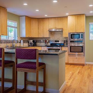 A modern kitchen with wooden cabinets, stainless steel appliances, and a kitchen island with bar stools.