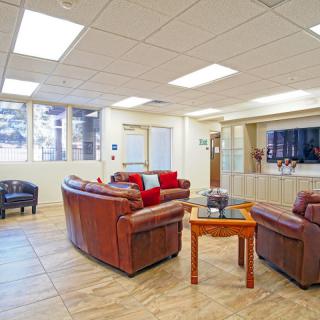 A cozy living room with leather sofas, a TV, and large windows.