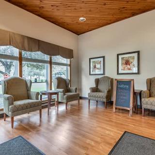 A cozy waiting room with comfortable armchairs and large windows letting in natural light.