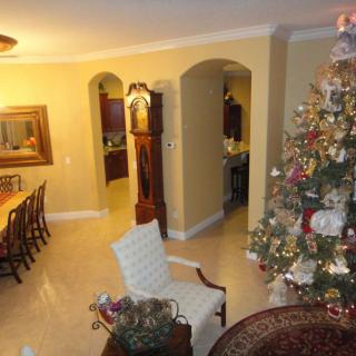 A warmly decorated living and dining area featuring a Christmas tree and a grandfather clock.
