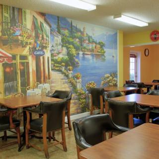 A cozy cafe interior with a colorful mural on the wall and neatly arranged tables and chairs.
