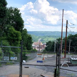 A scenic view of a city nestled in the hills, framed by greenery and power lines.
