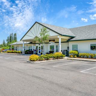 A single-story building with a parking lot and landscaping under a blue sky.