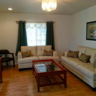A cozy living room with two cream-colored sofas, a wooden coffee table, and dark green curtains.
