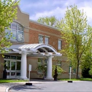 A modern building entrance surrounded by greenery and trees.
