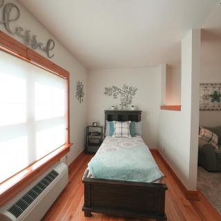 A cozy, minimalist bedroom with a single bed and ample natural light.