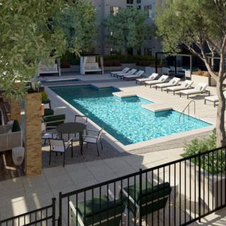 A modern outdoor swimming pool area with lounge chairs and a seating space surrounded by trees.