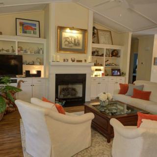 A cozy living room with a central fireplace, surrounded by comfortable seating and decorative shelves.