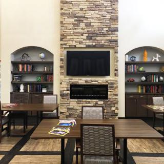 A cozy library with a stone fireplace and bookshelves lining the walls.