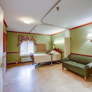 A cozy hospital patient room featuring a bed and a comfortable sofa.