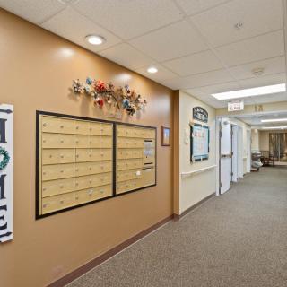 A hallway in an apartment building featuring decorative mailboxes and overhead lighting.