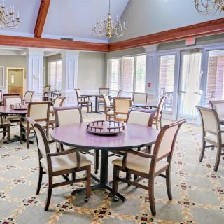 A spacious dining room with neatly arranged tables and chairs, illuminated by chandeliers.