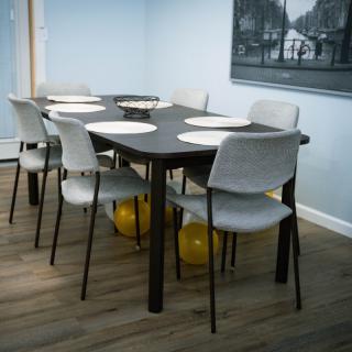 A dining room with a modern table set for six, featuring white chairs and balloons underneath.