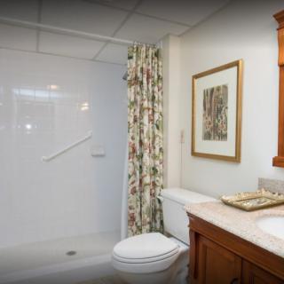 A clean and well-organized bathroom with a shower, toilet, and sink.