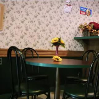 A cozy cafe table with a flower centerpiece against a patterned wallpaper backdrop.