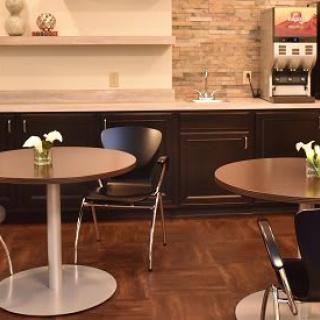A cozy cafe interior with round tables, chairs, and a coffee machine.