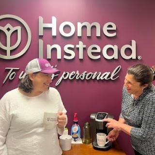 Two team members enjoying a light moment while preparing coffee at Home Instead.