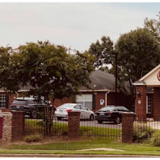 A quiet neighborhood scene featuring several houses, parked cars, and lush greenery.
