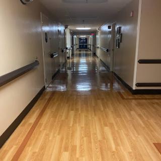A view down a well-lit corridor with wooden flooring.