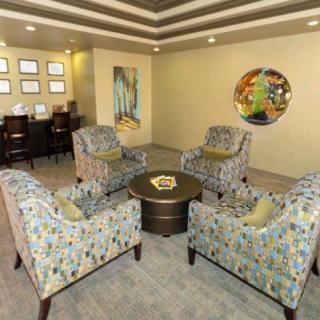 A modern living room with patterned armchairs arranged around a circular table, featuring contemporary artwork on the walls.