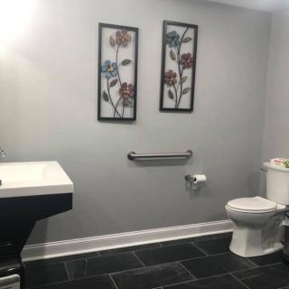 A modern bathroom with grey walls, featuring floral artwork, a toilet, and a sleek sink.