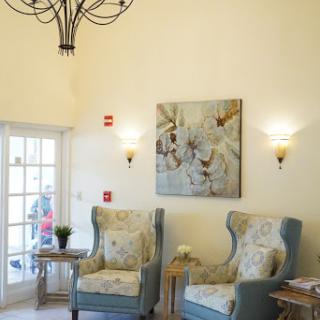 A cozy and elegant lobby area featuring comfortable chairs, tasteful wall art, and a beautiful chandelier.