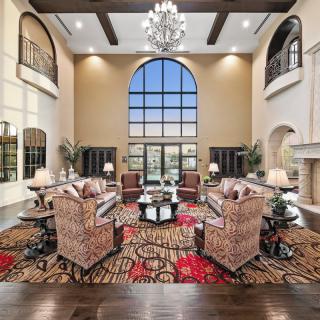 A luxurious living room with high ceilings, a large arched window, and elegant furnishings.