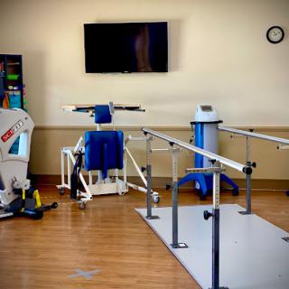A well-equipped physical therapy room featuring exercise machines, walking bars, and rehabilitation tools.