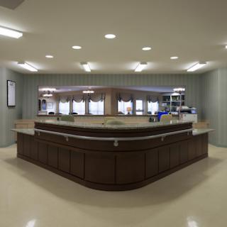 A modern reception area featuring a curved wooden counter and ample lighting.
