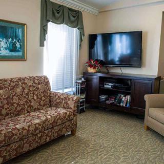 Cozy living room with patterned sofa, armchair, and a large television.