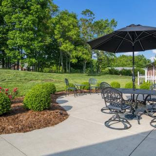 A sunny outdoor patio with furniture and a garden view.